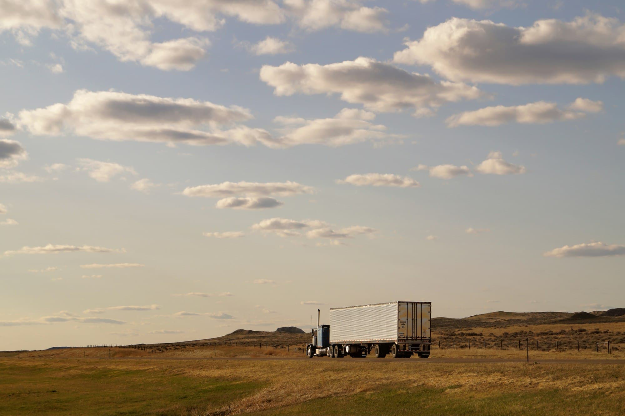Truck crossing open country under a wide sky